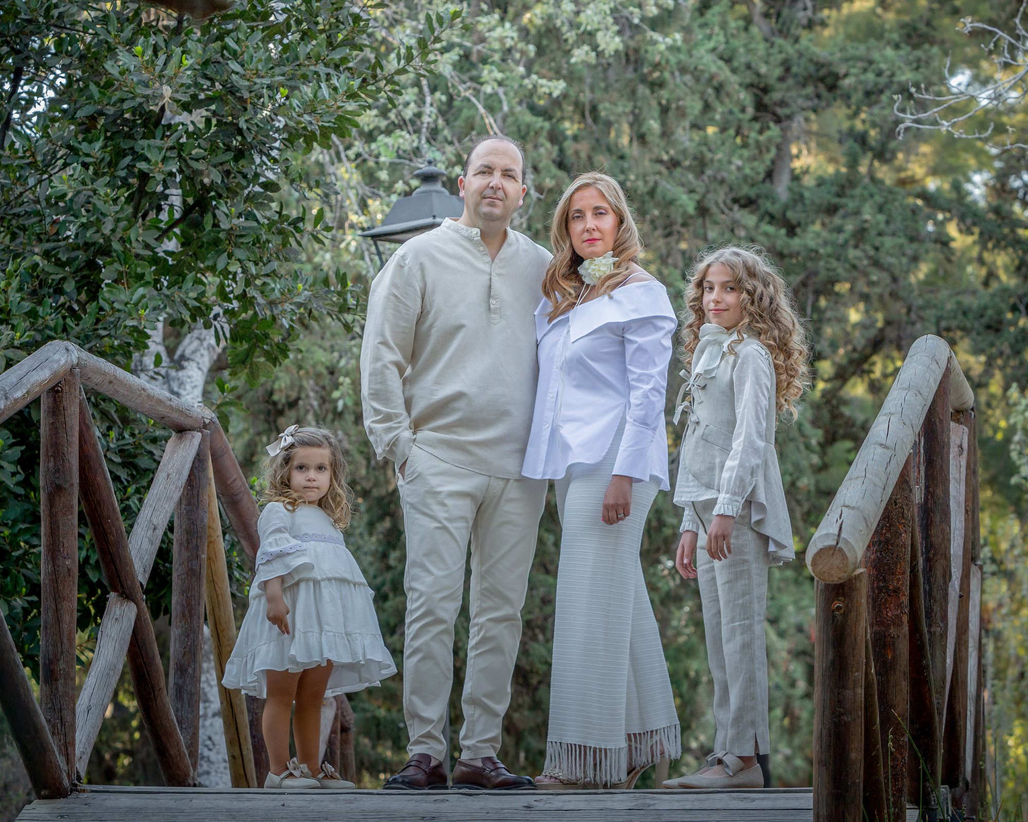 Fotografía familia vestidos de blanco encima de puente entre árboles