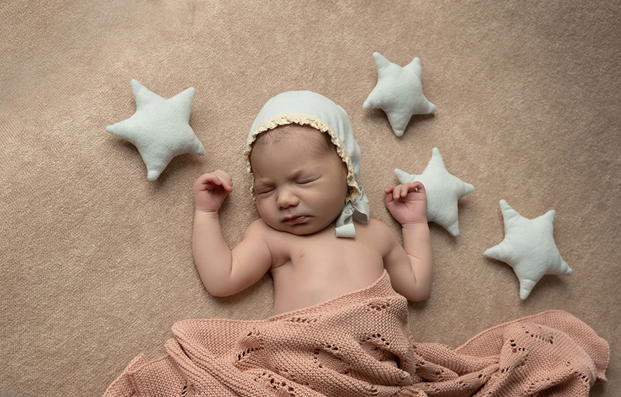 Magicasfotos Newborn (16) Fotografía de un recién nacido con telas rosas acostado en el suelo entre estrellas azules